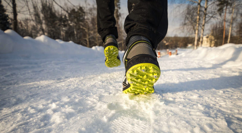 Człowiek w butach do biegania z żółtym bieżnikiem – dostosowanych do warunków zimowych