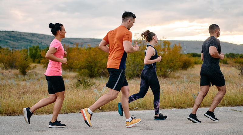 Grupa osób biegnąca w plenerze na pustej drodze